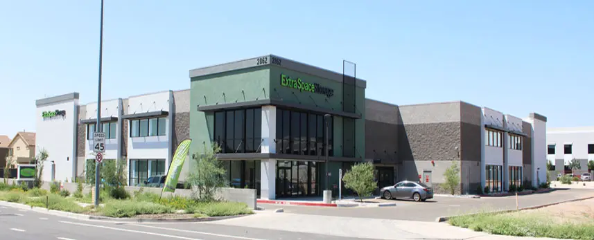 A large green building with cars parked in front of it.