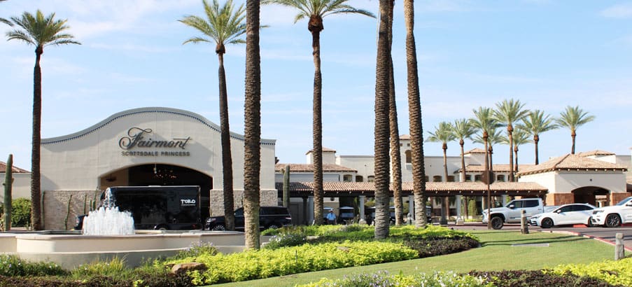 A view of palm trees and bushes in front of a building.