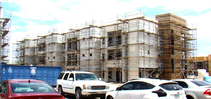 A building with scaffolding around it and cars parked in front of it.