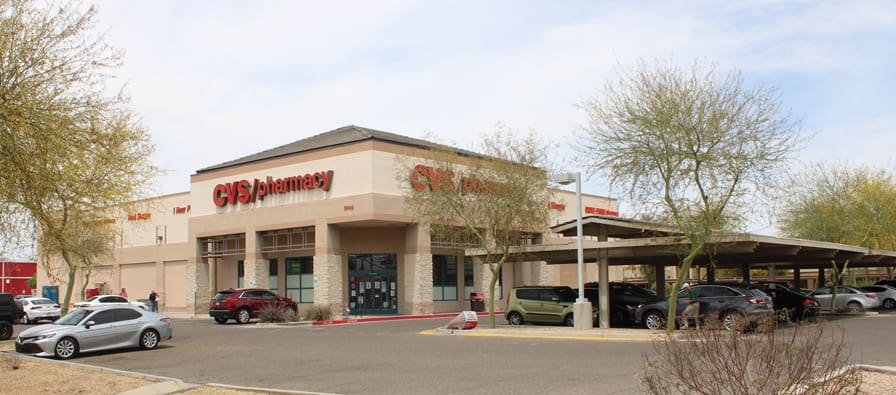 A large store front with cars parked in the parking lot.