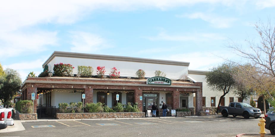 A restaurant with people standing outside of it.