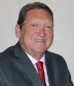 A man in a suit and tie smiling for the camera.